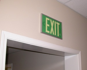 Green Exit Sign, mounted on the wall, with standard architectural framing system