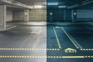 Picture showing a parking garage in light and darkness. EverGlow signs and marking glow in the dark and reveal the way to the exit